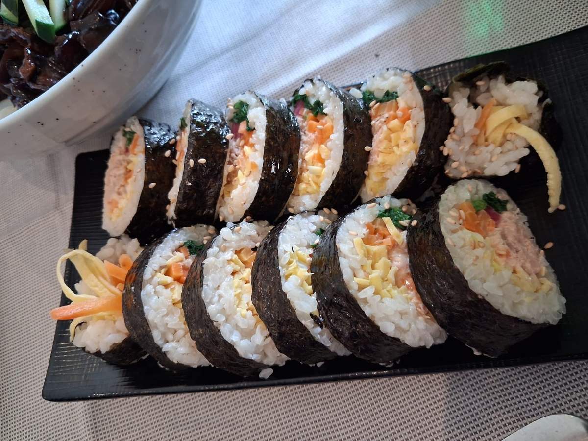 Kimbab pancetta e kimchi tagliato a dischetti su piatto nero