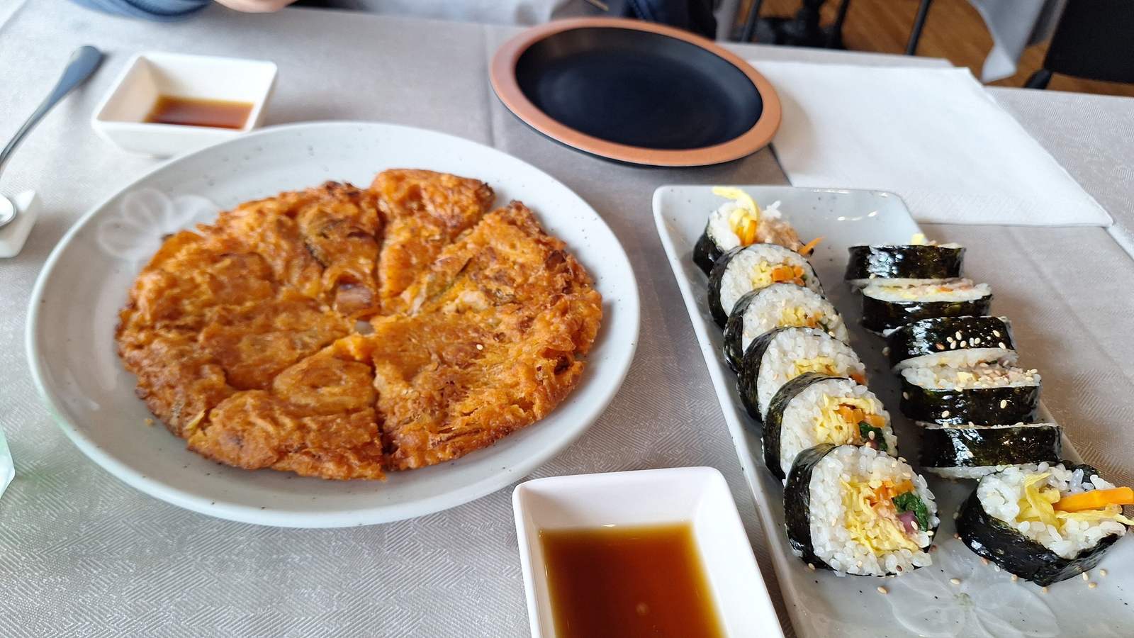 Kimchi jeon tagliato a spicchi e kimbab con salsa di soia su una tavola del Dream