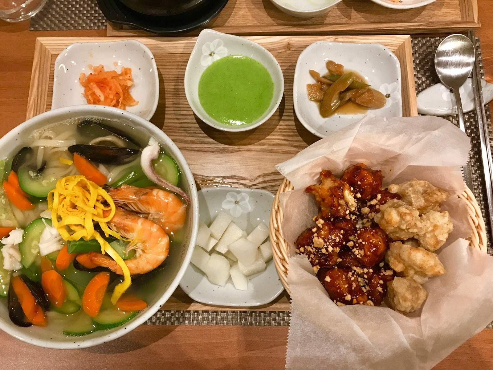 Vassoio di legno con banchan, verdure saltate e pollo fritto, su una tavola del Dream