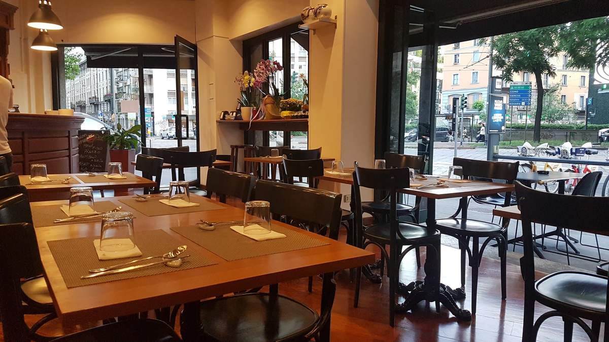La sala con le vetrate aperte sulla piazza e i tavoli apparecchiati
